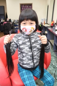 切ったばかりの髪を手にする横田凛さん＝姫路市網干区垣内北町