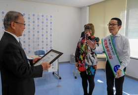 委嘱状の「義一」の読み方に詰まった岩見武三町長にツッコミを入れる市川義一さん（右）と和田美枝さん＝市川町役場