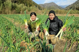 山あいの畑で収穫したまちこネギをＰＲする東勇太さん（右）と永瀬静さん＝市川町上牛尾