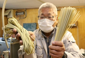 モロヘイヤの粉末を練り込んだ「円心モロどん」を手に持つ平田製麺所の平田善彦さん＝上郡町上郡