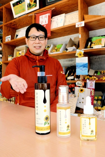 ヒマワリ油を使ったスキンケア商品「さようのめぐみ」と、商品化を企画した平福祐介さん＝南光ひまわり館