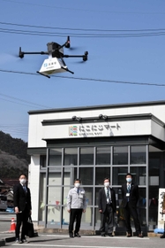 弁当を載せて運ぶドローンを見守る関係者たち＝宍粟市波賀町上野