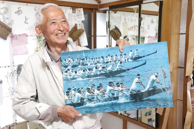出場したペーロン競漕の写真を持つ川崎久令さん＝相生市