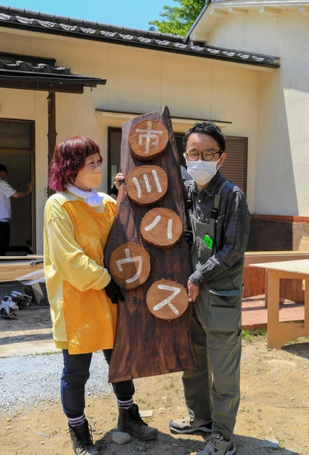 「市川ハウス」の看板と並ぶ市川さん（右）と和田さん＝市川町下牛尾