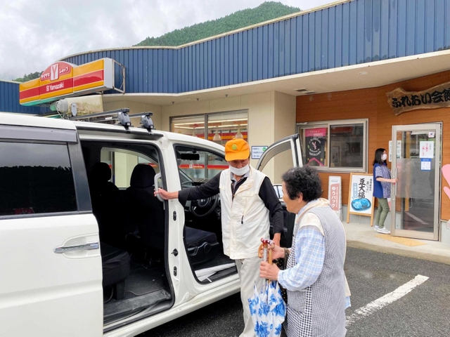 「連絡をくれたら迎えにも行ったのに」。歩いて来店し、買い物を終えた客を自宅へ送るため、車に案内する前嶋茂徳さん（左）＝神河町長谷