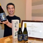 フランスの品評会でプラチナ賞に輝いた日本酒「播州一献　純米大吟醸　山田錦」を掲げる壺阪専務＝山陽盃酒造