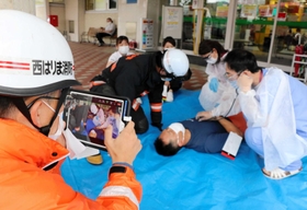 負傷者の情報をタブレット端末で病院と共有し、搬送の訓練に取り組む消防署員＝佐用町佐用