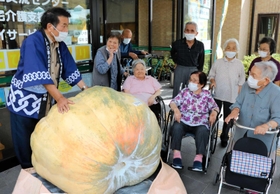 巨大カボチャにびっくりする高齢者と本田三郎さん（左）＝佐用町福吉