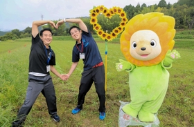 ハート形に並べたヒマワリの隣でハートのまちをアピールするマスコットキャラクター「ひまりん」と市川町職員＝市川町奥