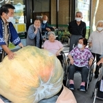 巨大カボチャにびっくりする高齢者と本田三郎さん（左）＝佐用町福吉