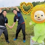 ハート形に並べたヒマワリの隣でハートのまちをアピールするマスコットキャラクター「ひまりん」と市川町職員＝市川町奥
