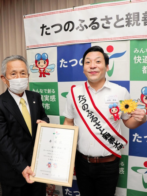 たつの市のふるさと親善大使に就任した田渕章裕さん（右）。山本実市長の依頼で胸のヒマワリを市公式キャラクターにつけ替えた＝東京都千代田区