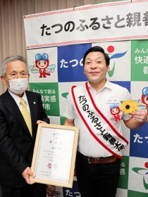 たつの市のふるさと親善大使に就任した田渕章裕さん（右）。山本実市長の依頼で胸のヒマワリを市公式キャラクターにつけ替えた＝東京都千代田区