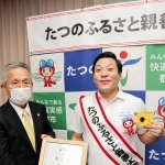 たつの市のふるさと親善大使に就任した田渕章裕さん（右）。山本実市長の依頼で胸のヒマワリを市公式キャラクターにつけ替えた＝東京都千代田区