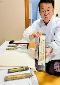間喜兵衛が短歌を記した短冊を持つ飯尾義明宮司＝赤穂大石神社