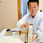 間喜兵衛が短歌を記した短冊を持つ飯尾義明宮司＝赤穂大石神社