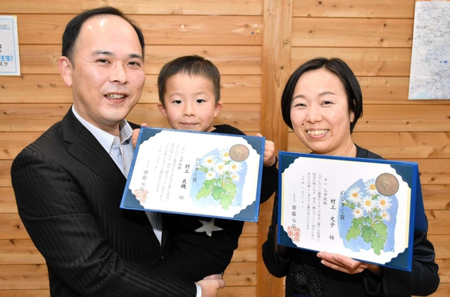 転落した男性を救助し、のじぎく賞を受けた村上良機さん（左）と文子さん。中央は暁彦ちゃん＝宍粟市山崎町上比地
