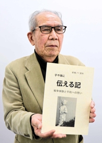 改訂した文集を手に平和への思いを語る松浦暁了さん＝たつの市内