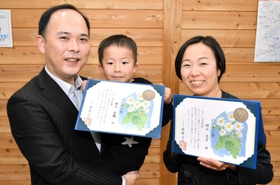 転落した男性を救助し、のじぎく賞を受けた村上良機さん（左）と文子さん。中央は暁彦ちゃん＝宍粟市山崎町上比地