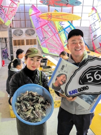 現役時代に掲載された競技雑誌を持つ神頭士郎さんと妻の郁子さん。ウインドサーフィンの帆がインテリアになっている＝たつの市御津町