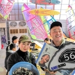 現役時代に掲載された競技雑誌を持つ神頭士郎さんと妻の郁子さん。ウインドサーフィンの帆がインテリアになっている＝たつの市御津町