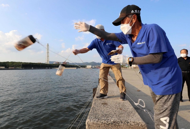 仕掛けを投げ入れていくボランティアの男性ら＝赤穂市中広（撮影・辰巳直之）