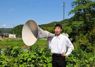 憧れの屋外スピーカーを手に入れた成田啓さん。奥は一番好きな防災行政無線＝市川町下瀬加