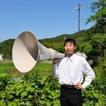 憧れの屋外スピーカーを手に入れた成田啓さん。奥は一番好きな防災行政無線＝市川町下瀬加