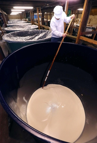 新酒の仕込み作業が進む老松酒造の酒蔵。タンク内のもろみを櫂棒でかき混ぜる杜氏＝宍粟市山崎町山崎（撮影・辰巳直之）