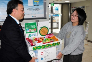 みなと銀行赤穂支店に寄せられた食品を高尾広志支店長（左）から受け取る、あこう子ども食堂の岩崎由美子さん＝赤穂市加里屋