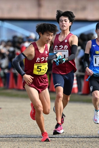 男子・たつの市の１区亀田仁一路選手（右）からたすきを受ける２区三浦彰太選手＝加古川市の加古川河川敷マラソンコース（撮影・風斗雅博）