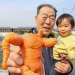 今にも踊り出しそうなニンジンを持つ山本士郎さんとひ孫の悠透ちゃん＝福崎町福崎新