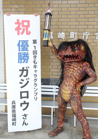 地域振興課職員お手製のトロフィーを持って喜ぶガジロウ＝福崎町南田原、福崎町役場