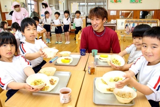 卵料理を味わう園児に「もっと卵を作ってね」と声をかけられ、笑顔を見せる田隅養鶏場の田隅博也取締役（右から３人目）＝いちかわ西こども園