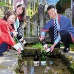 宍粟市の地酒「三笑」の蔵出し式で「ぬくゐの泉」に酒瓶を浸す酒蔵関係者ら＝宍粟市一宮町能倉