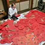魔よけを意味する赤のうちわに宮司が文字を入れていく＝赤穂市坂越