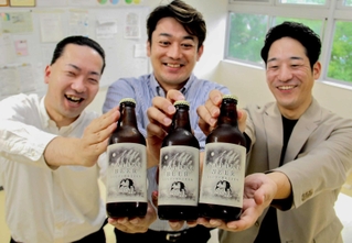 福崎町特産のもち麦を使った地ビールを開発した町商工会青年部の小幡勇介さん（中央）ら＝姫路市内