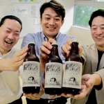 福崎町特産のもち麦を使った地ビールを開発した町商工会青年部の小幡勇介さん（中央）ら＝姫路市内
