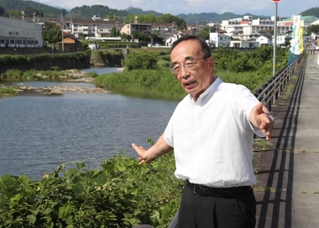 佐用川を前に豪雨当時を振り返る佐用町の庵逧典章町長＝佐用町佐用（撮影・辰巳直之）