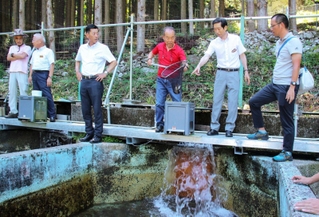 南あわじ市の守本憲弘市長（右から２人目）に養殖するヤマメを見せる長谷漁協の大和正美組合長（同３人目）＝神河町川上