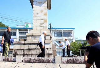 遺族会の会員らが慰霊碑に手を合わす様子を撮影する映像制作会社のスタッフら＝市川町東川辺