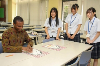 生徒に教わりながら福笑いを体験するミガンさん（左）＝神河町福本