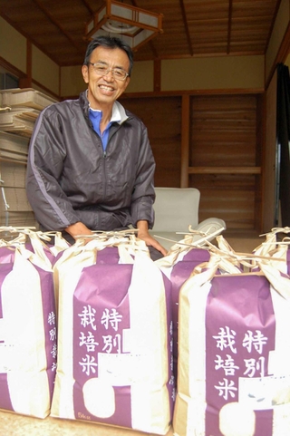 ２、３歳児健診受診者宅に送る特別栽培の「タガメの里自然米」を前に話す笹山和朗さん＝上郡町高山