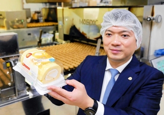 米国で人気のスイスロール（ロールケーキ）を手にする田口翔一副社長＝相生市陸東汐見塚