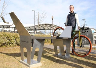 自転車をかけられる馬車をモチーフにした形のベンチと、作者のケビン・ネルさん＝福崎町福田