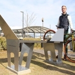 自転車をかけられる馬車をモチーフにした形のベンチと、作者のケビン・ネルさん＝福崎町福田