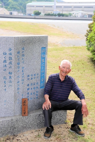 新相生ペーロン音頭の碑と相生湾のそばで思い出に浸る川崎久令さん＝相生市、ポート公園