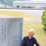 新相生ペーロン音頭の碑と相生湾のそばで思い出に浸る川崎久令さん＝相生市、ポート公園