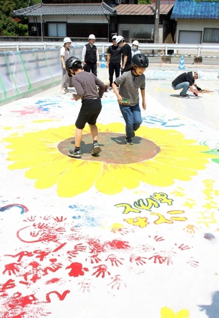 靴の裏にペンキを塗って足踏みで町花のヒマワリを描く子どもたち＝市川町下牛尾