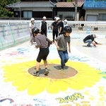 靴の裏にペンキを塗って足踏みで町花のヒマワリを描く子どもたち＝市川町下牛尾